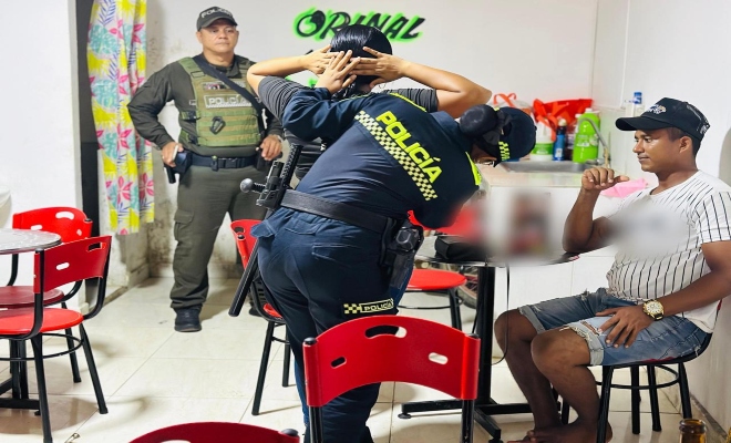 dos uniformados realizando registro a dos ciudadanos en establecimiento abierto al publico 