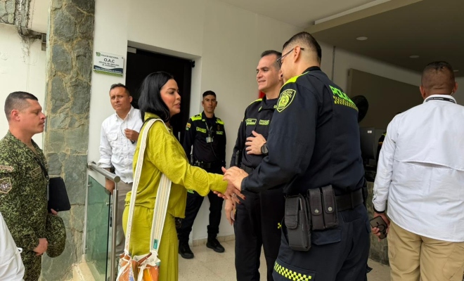 una ciudadana dando la mano a un uniformado  y a su alrededor cuatro personas más 
