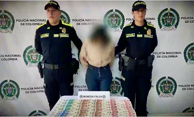 una mujer capturada, una mesa con billetes falsos y la acompañan 2 funcionarios policiales