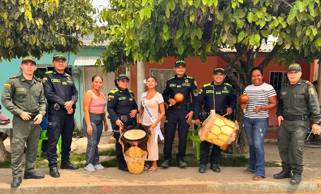 Cinco funcionarios policiales junto a tres ciudadanas sonriendo con instrumentos mucicales