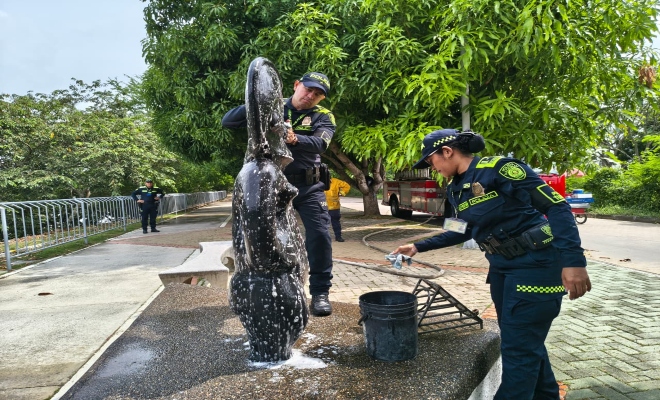Dos policías realizando limpieza en el monumento y un policía prestando seguridad 