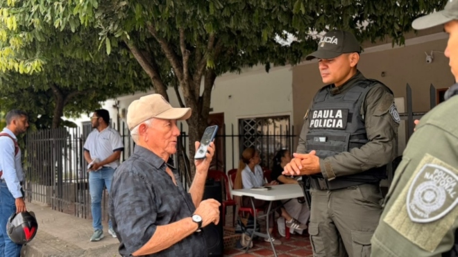 un funcionario de la policía Nacional orientando a un ciudadano sobre la extorción y la línea 165