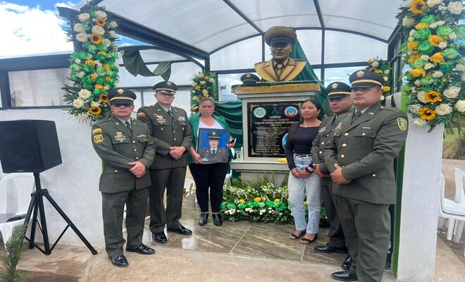 Cuatro polic&iacute;as con dos mujeres frente ha placa conmemorativa 