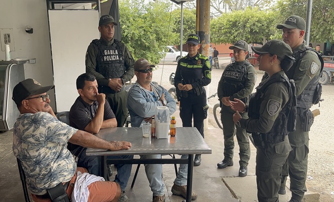 En un establecimiento abierto al público, cinco funcionarios de la Policía Nacional socializan con tres ciudadanos las diferentes modalidades de extorsión y brindan recomendaciones para prevenir este delito