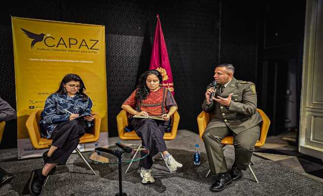 Dos mujeres un pol&iacute;cia en un conversatorio.