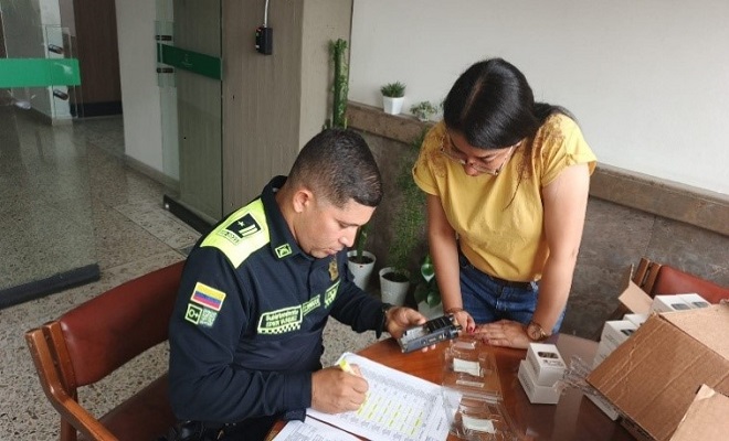 Funcionario de la Policía Nacional recibiendo y verificando los 20 radios de comunicación entregados en compañía de una funcionaria de la Gobernación.