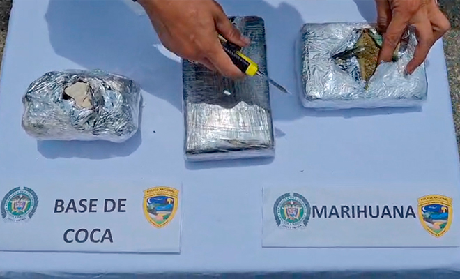 Paquetes de base de cocaína y marihuana en mesa con mantel blanco.