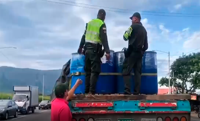 Dos polic&iacute;as encima de una tractomula con canecas azules y un ciudadano
