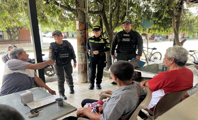 Tres funcionarios de la Policía Nacional, uno de ellos saludando a uno de los tres ciudadanos que reciben información sobre la prevención de la extorsión y el secuestro