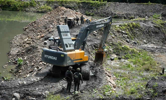 Policías junto una excavadora