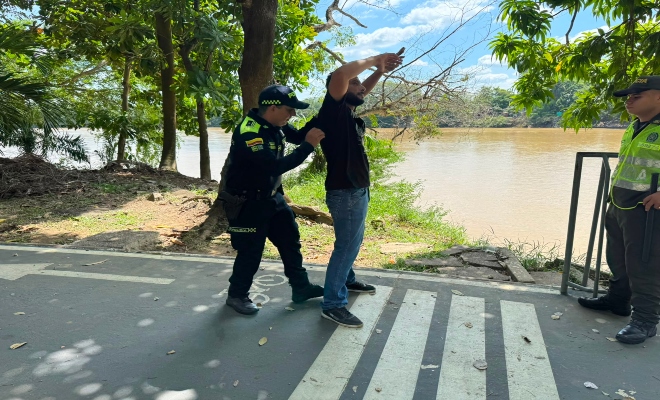 dos uniformados con un ciudadano practicándole registro a personas en ciclovía del parque principal de la ciudad de montería    