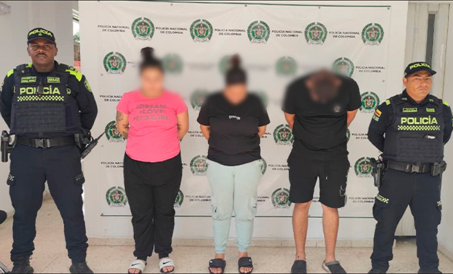 Dos policías sostienen a tres capturados en flagrancia.