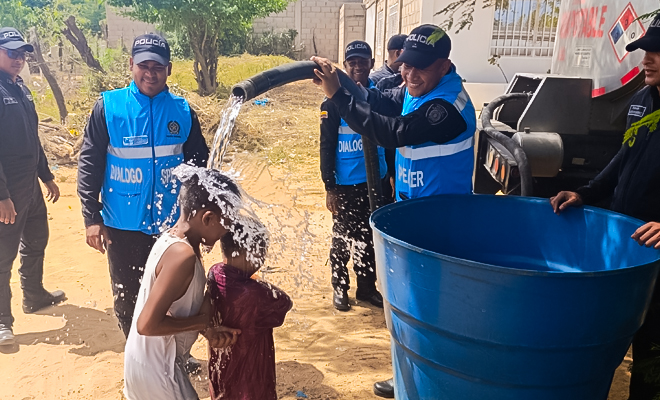 Policías de la Policía Nacional entregan agua potable a familias del barrio Brisas del Mar, en Riohacha, llevando apoyo y bienestar a la comunidad