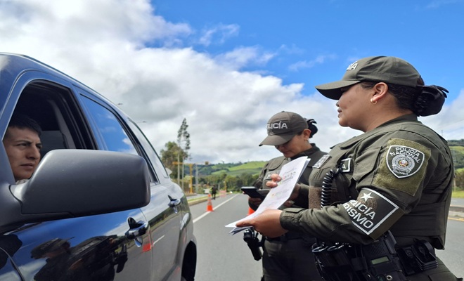 Dos funcionarios policiales frente a un automóvil dando recomendaciones 