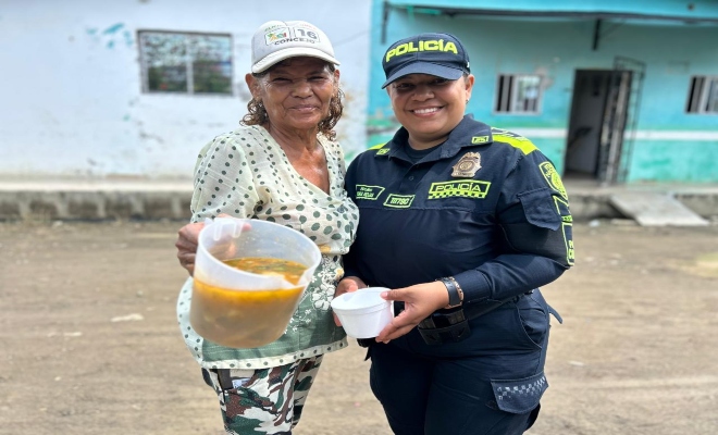 una uniformada de la polic&iacute;a nacional con  una ciudadana compartiendo comida