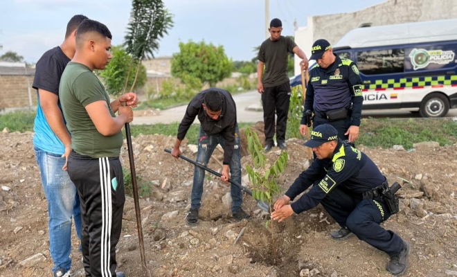 dos uniformados de la polic&iacute;a y cuatro ciudadanos organizando espacios y sembrando arboles fomentar el cuidado del medio ambiente mediante la recuperaci&oacute;n y embellecimiento de las zonas comunes.