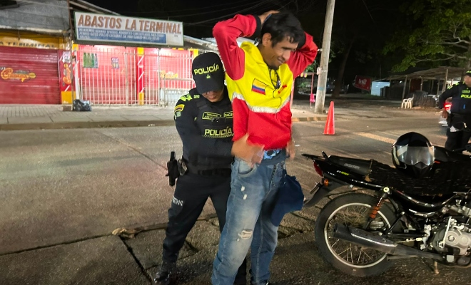 funcionario policial realizando registro a persona a un ciudadano junto a una motocicleta