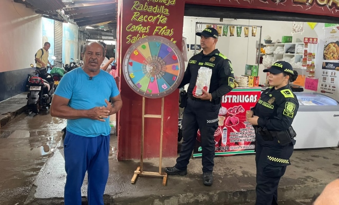 Dos funcionarios policiales junto a un ciudadano en actividad dirigidas a comerciantes, visitantes del mercado del sur