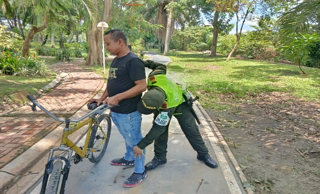 un uniformado de la polic&iacute;a nacional realiza un registro a personas en el parque principal de la ciudad de Monter&iacute;a