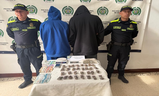Policías custodian personas capturadas, en la mesa se observan los elementos incautados