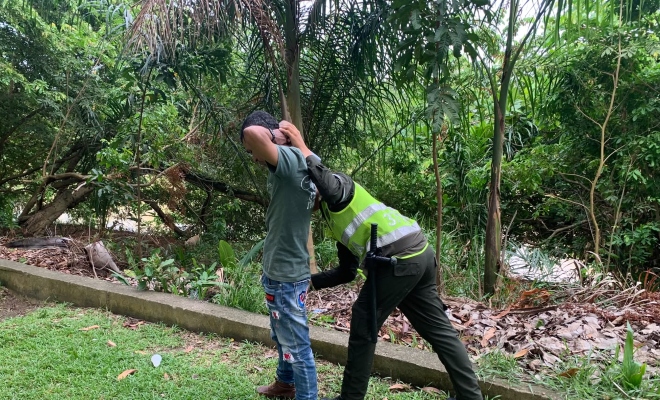 Funcionario policial realizando registro a persona en zona verde 