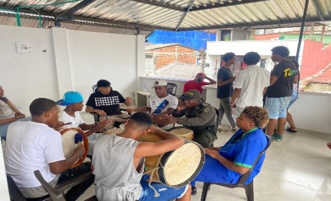 Varios jóvenes tocando instrumentos musicales con un policía.