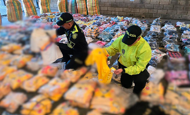 Dos policías revisando camisetas incautadas