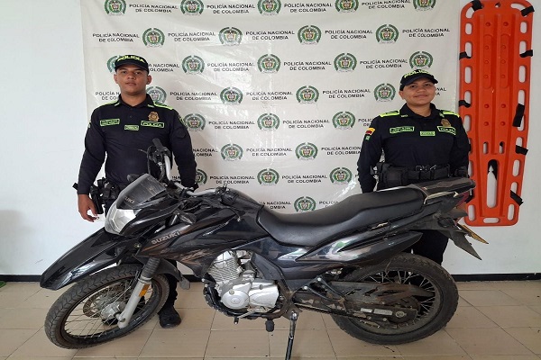 Dos policías junto a una motocicleta recuperada
