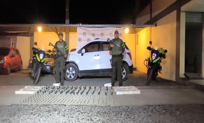 Dos policìas con material bèlico incautado granadas, un vehiculo al fondo y municiòn 