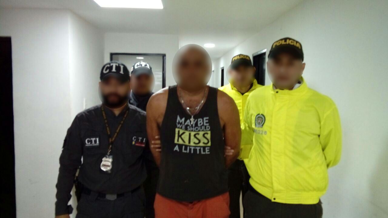foto de un hombre capturado, escoltado por dos policías y dos funcionarios del CTI