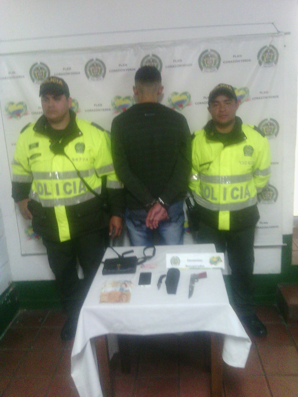 Un hombres de espaldas rodeados por dos policías