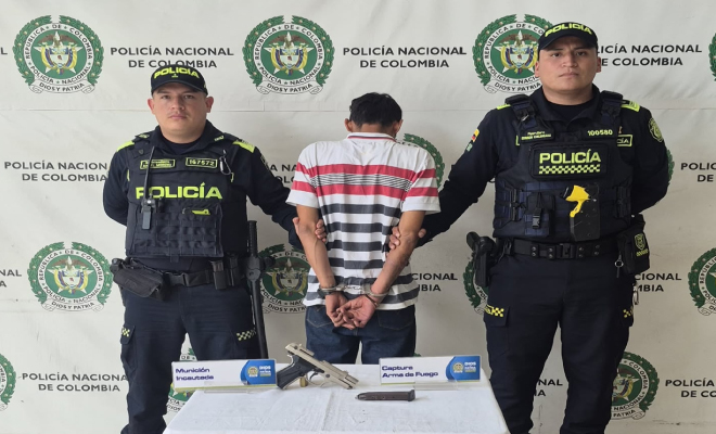 Hombre capturado en medio de dos Policías, en frente arma incautada