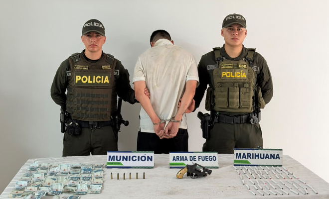 Hombre capturado en medio de dos Policías, en frente elementos incautados