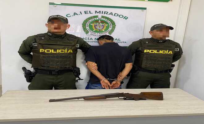 Dos policías con un capturado con arma de fuego incautada durante procedimiento policial.
