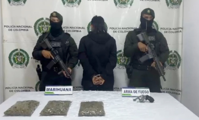 Hombre capturado en medio de dos polic&iacute;as, en frente elementos incautados