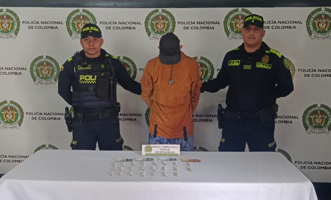 Hombre capturado en medio de dos Policías y incautación de estupefacientes encima de una mesa
