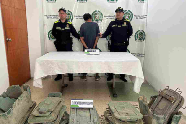 Hombre capturado en medio de dos policías, en frente elementos incautados