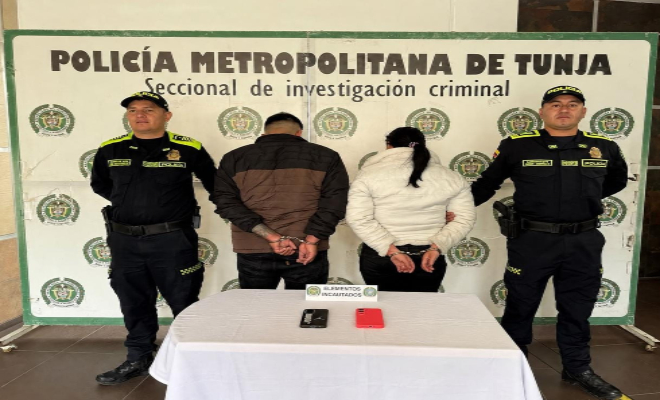 dos policías en cada lado y dos personas capturadas una mesa con elementos incautados