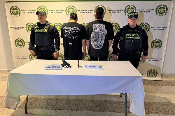 Dos Policías, dos capturados, mesa con arma de fuego