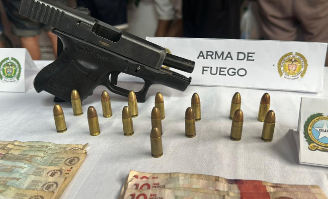 Arma de fuego incautada y cartuchos encima de una mesa