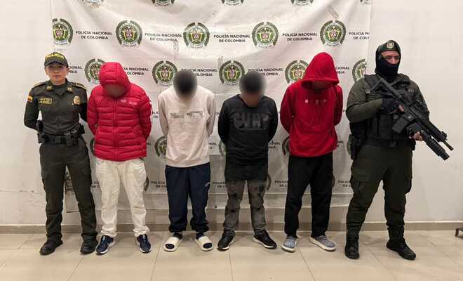 Cuatro hombres capturados con dos policías a su lado