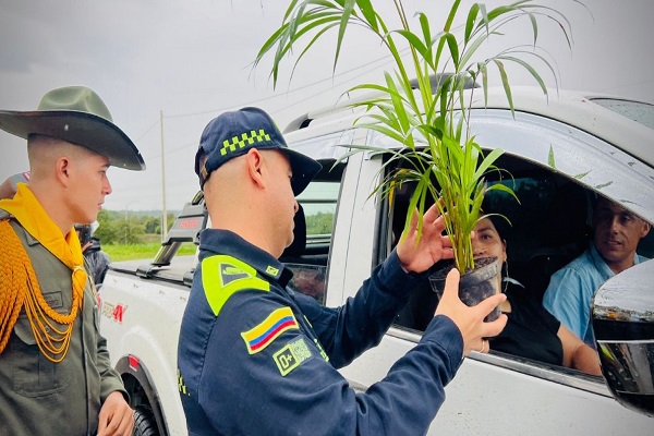 El señor Coronel Héctor Jairo Betancourt Rojas con funcionario de carabineros compartiendo palma a una ciudadana en el marco de la estrategia Semana Santa Segura