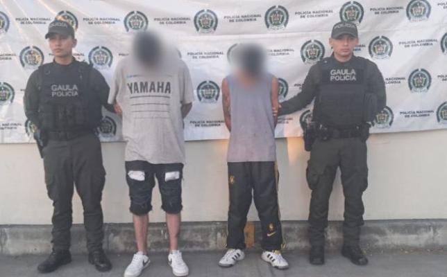 dos policías al lado de dos hombres capturados