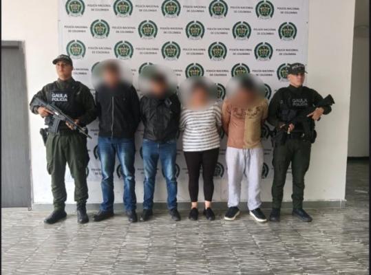 dos policías al lado de cuatro personas capturadas