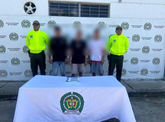 dos polic&iacute;as al lado de tres hombres capturados