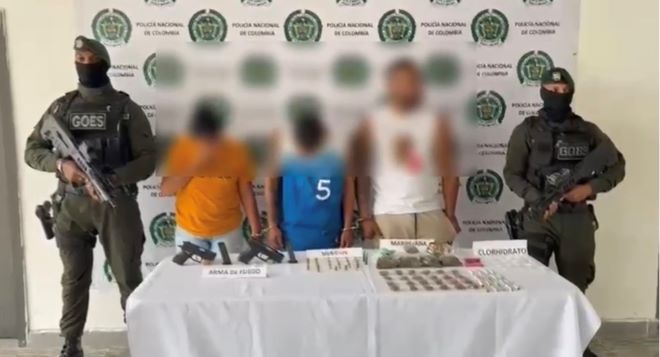 dos polic&iacute;as al lado de tres hombres capturados con material incautado