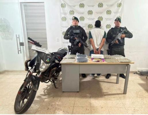 dos policías al lado de un hombre capturado con material incautado