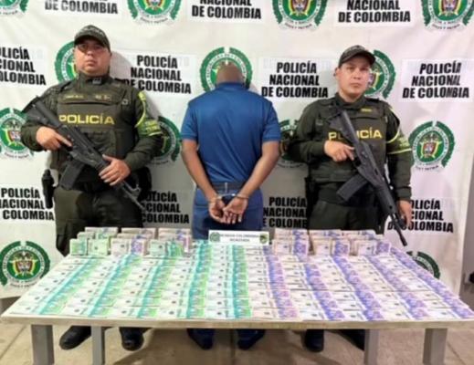 Dos policías en el medio un hombre capturado con dinero
