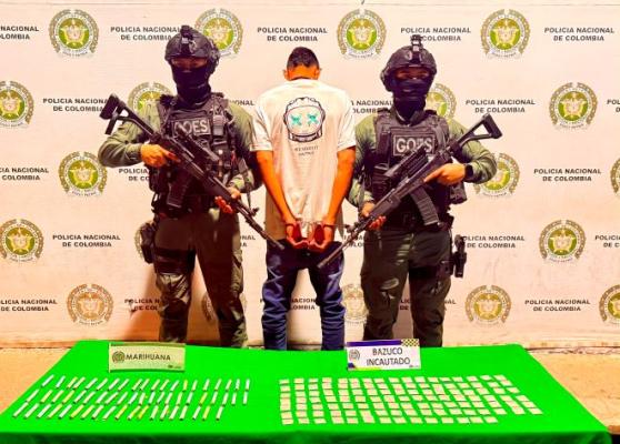 dos polic&iacute;as al lado de un hombre capturado con estupefacientes