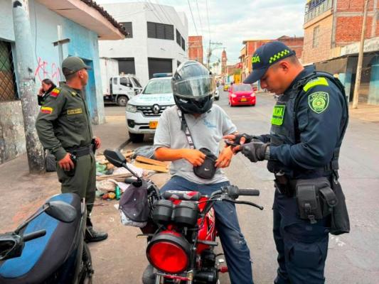 dos policías al lado de un hombre realizando registro a persona